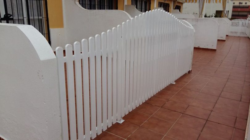 Valla blanca de madera en un patio con superficie de cerámica terracota.